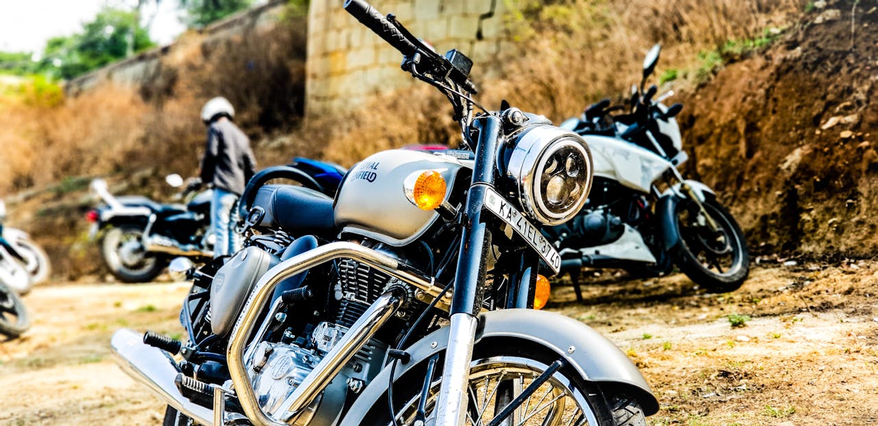Close-up of a classic motorcycle parked outdoors with other bikes, conveying adventure and freedom.